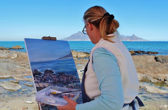 une femme fait de la peinture au bord de la mer
