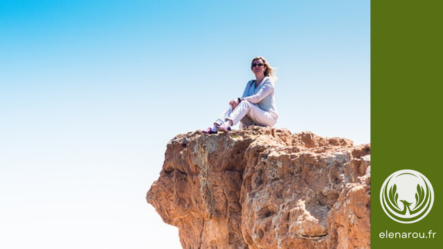 une femme assise au sommet du rocher